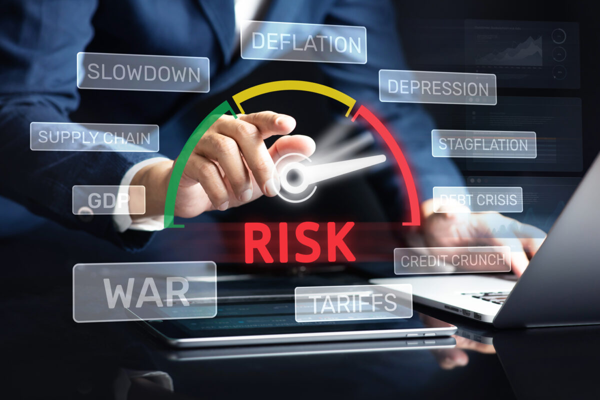 Hand adjusting a risk meter with economic indicators like inflation, slowdown, and debt crisis displayed on a digital dashboard.
