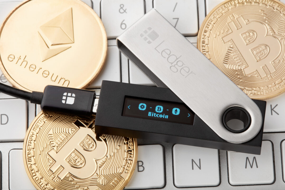 Ledger hardware wallet securing Bitcoin and Ethereum on a keyboard, illustrating safe storage principles in a cryptocurrency investing guide.